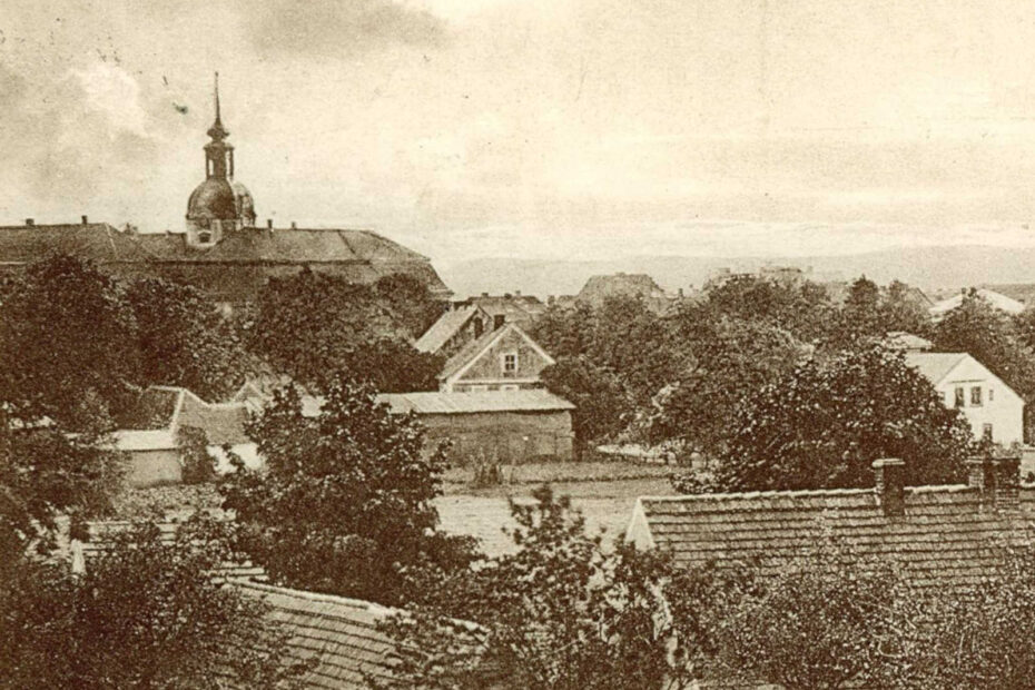 Bild aus Lieberose aus 1928, das von oben aufgenommen wurde. Zu sehen sind mehrere Dächer und eine Kirchturmspitze.