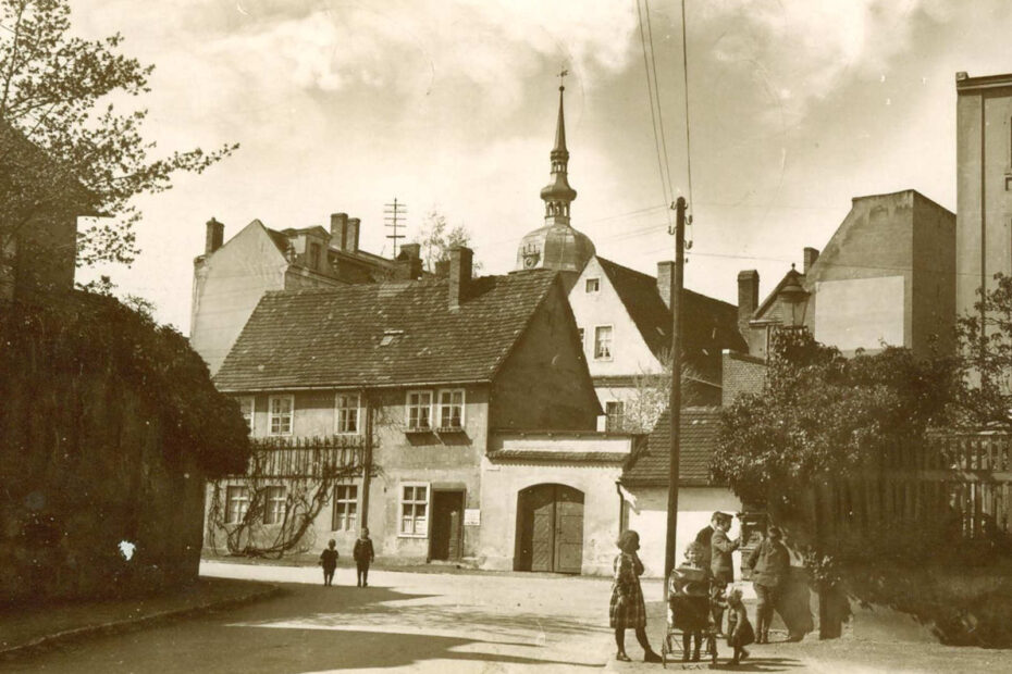 Lübben 1923. Eine Straße mit mehren Kindern. Ein Haus, hinter dem mehrere andere Häuser herausragen.