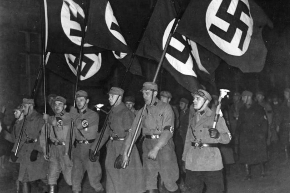 SA Aufmarsch am Abend der Machtergreifung von Hitler. Eine Reihe von uniformierten SA Soldaten ist zu sehen mit Hakenkreuzbinde und Hakenkreuzfahnen.