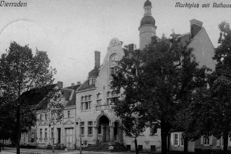 Postkarte aus 1911 aus Vierraden, das den Marktplatz mit Rathaus zeigt. Zu sehen ist ein prächtiges Gebäude mit Turmspitze, rechts und links verdeckt durch Bäume.